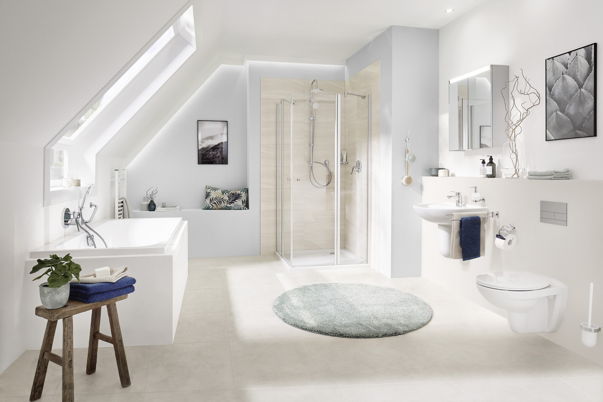 Das Bild zeigt ein Badezimmer mit Dachschräge der Marke SANIBEL. Die Keramik ist in weiß gehalten, es ist eine Badewanne und eine Dusche mit einer Duschabtrennung und ein Waschtisch ohne Waschtischunterschrank zu sehen.